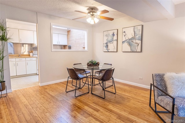 dining area with light wood finished floors, a textured ceiling, baseboards, and a ceiling fan