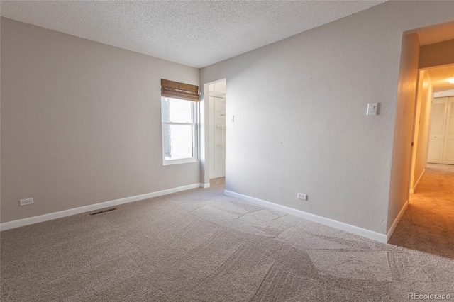 empty room featuring visible vents, baseboards, and a textured ceiling