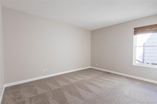 empty room with visible vents, baseboards, carpet, and a textured ceiling