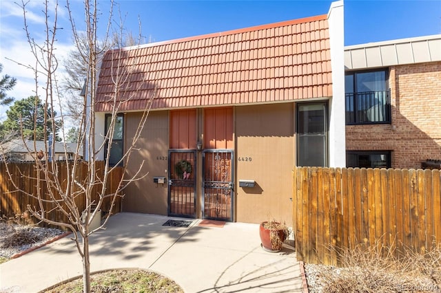 exterior space with a tiled roof, fence, and brick siding