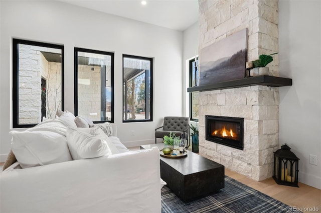 living room with a fireplace, baseboards, and wood finished floors