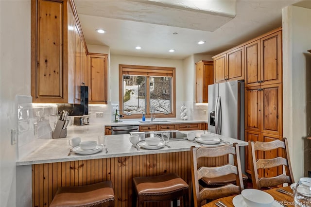 kitchen featuring sink, a breakfast bar area, decorative backsplash, kitchen peninsula, and stainless steel appliances