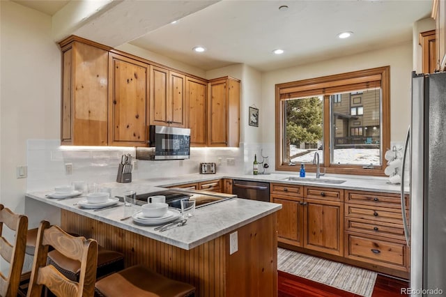 kitchen featuring kitchen peninsula, backsplash, stainless steel appliances, and sink