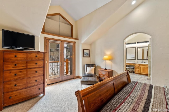 carpeted bedroom with connected bathroom, access to outside, and high vaulted ceiling