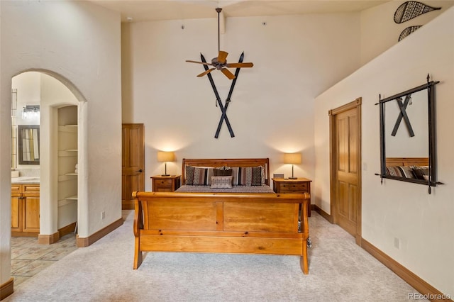 bedroom with ensuite bathroom, light colored carpet, and high vaulted ceiling