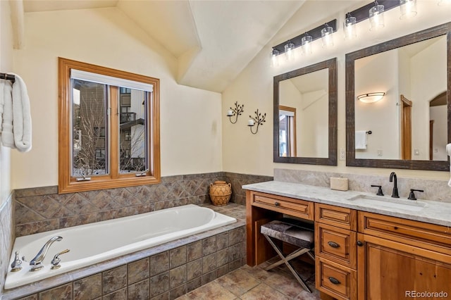 bathroom with tile patterned floors, a relaxing tiled tub, vanity, and vaulted ceiling