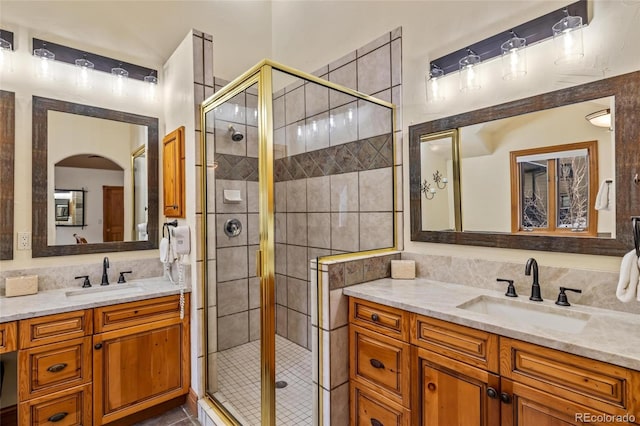 bathroom featuring vanity, tasteful backsplash, and a shower with door