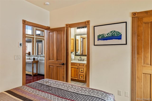 bedroom with light hardwood / wood-style floors, ensuite bath, and sink