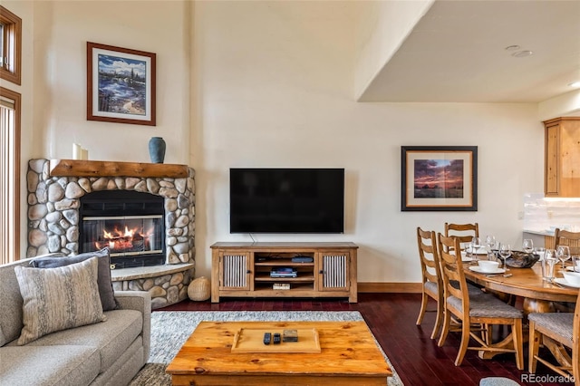 living room featuring a stone fireplace and dark hardwood / wood-style flooring