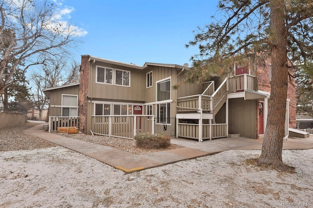 rear view of property featuring stairs and a jacuzzi