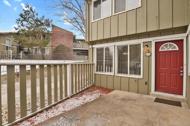 doorway to property with board and batten siding and fence