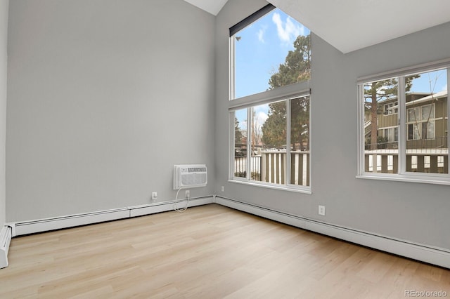 spare room with a wealth of natural light, vaulted ceiling, a baseboard heating unit, and wood finished floors