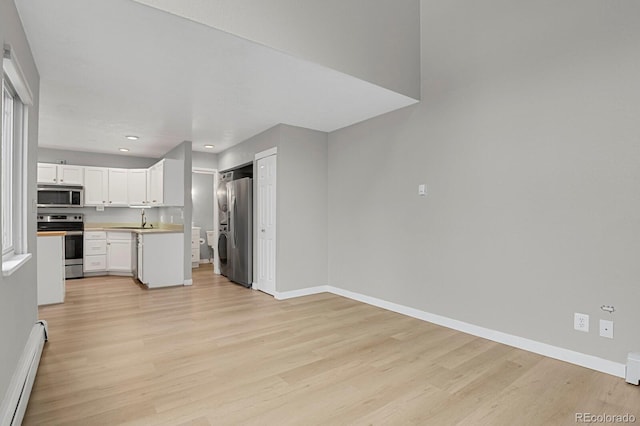 kitchen with baseboards, light wood-type flooring, baseboard heating, and stainless steel appliances