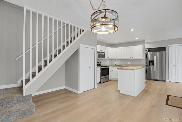 kitchen with light wood finished floors, recessed lighting, a sink, stainless steel appliances, and white cabinetry