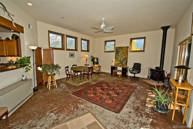 living area featuring ceiling fan and a wood stove