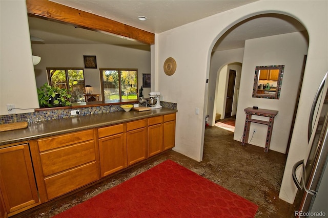 kitchen featuring beam ceiling, fridge, and dark carpet