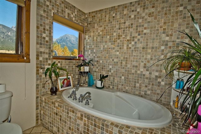 bathroom featuring a mountain view, a relaxing tiled tub, tile walls, and toilet