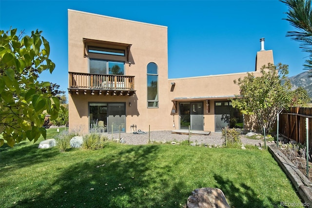 rear view of property featuring a balcony and a lawn