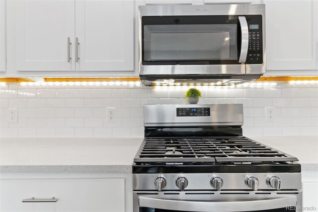 interior details featuring appliances with stainless steel finishes, white cabinets, backsplash, and light stone counters