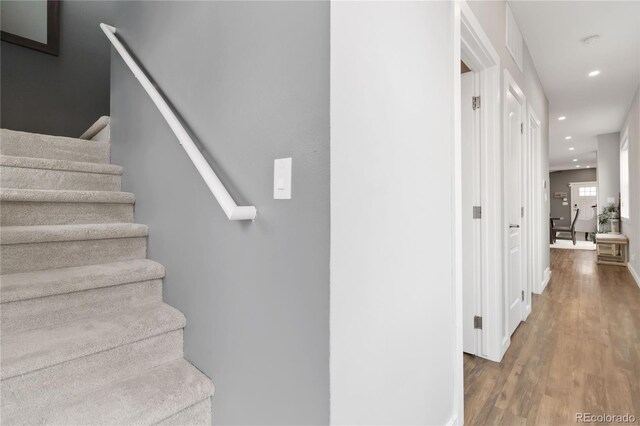 staircase featuring baseboards, wood finished floors, and recessed lighting