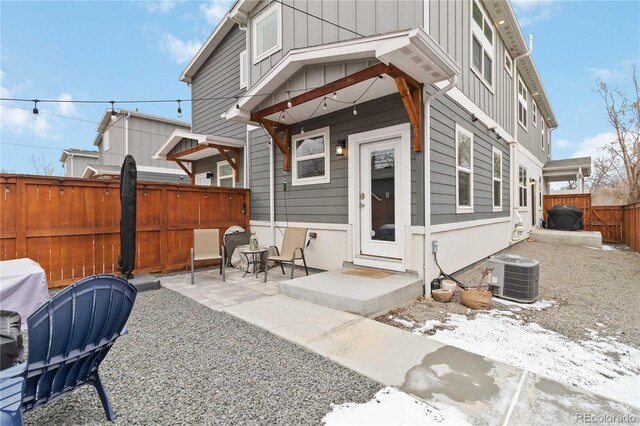 back of house featuring board and batten siding, a patio area, central AC, and a fenced backyard