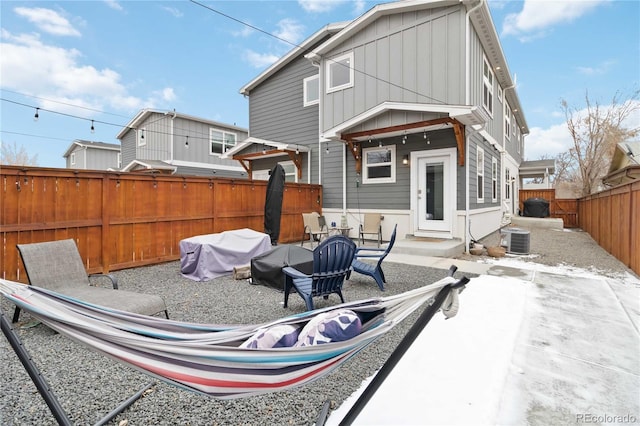 rear view of house featuring central air condition unit, a fenced backyard, and board and batten siding