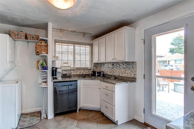 kitchen featuring tasteful backsplash, dishwasher, stacked washer and clothes dryer, white cabinetry, and a sink