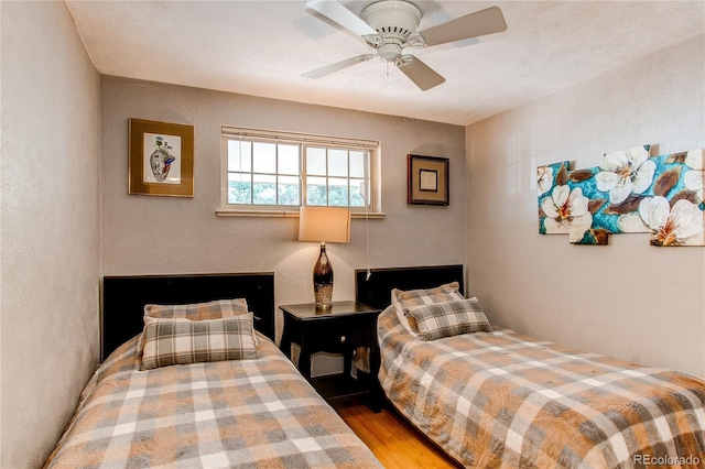 bedroom featuring a ceiling fan, wood finished floors, and a textured wall