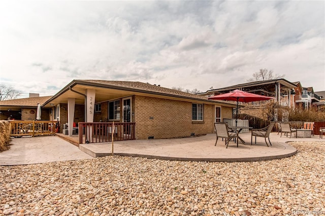 rear view of house featuring a patio area, brick siding, and crawl space