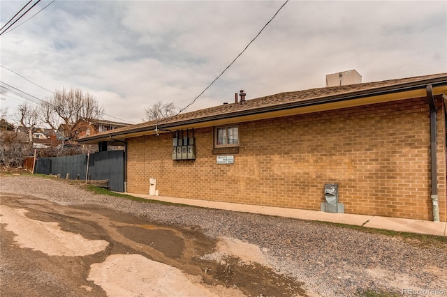 view of side of home with fence and brick siding