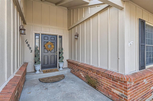 property entrance with board and batten siding and brick siding