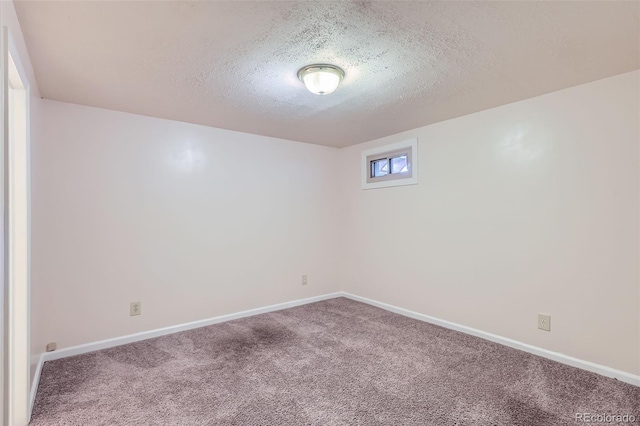 carpeted spare room with a textured ceiling and baseboards