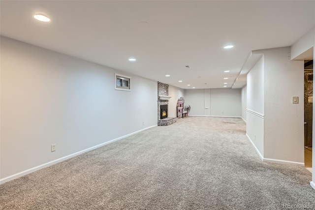 finished basement with light carpet, a brick fireplace, baseboards, and recessed lighting