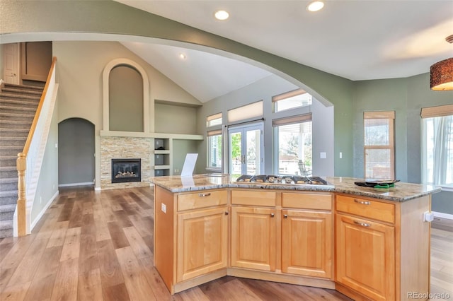 29852 E 163rd Pl, Brighton, CO 80603 - kitchen with light wood-style floors, stainless steel gas stovetop, open floor plan, light stone countertops, and vaulted ceiling