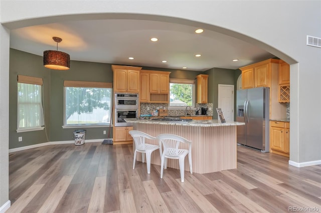 29852 E 163rd Pl, Brighton, CO 80603 - kitchen featuring appliances with stainless steel finishes, light wood-type flooring, arched walkways, a kitchen island, and backsplash