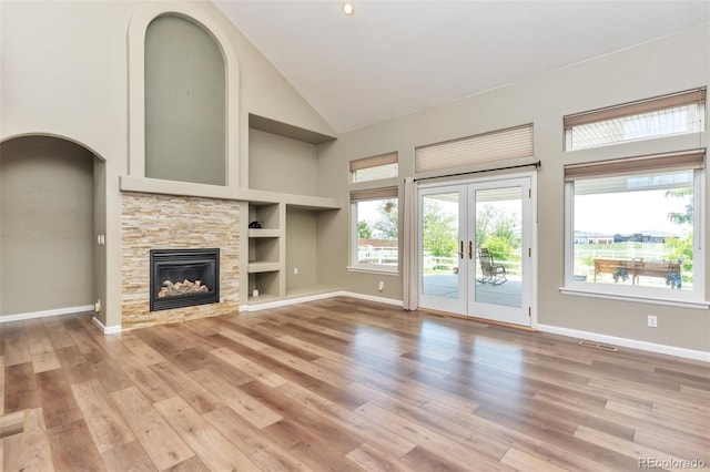 29852 E 163rd Pl, Brighton, CO 80603 - unfurnished living room with high vaulted ceiling, light wood-style floors, built in shelves, french doors, and a fireplace