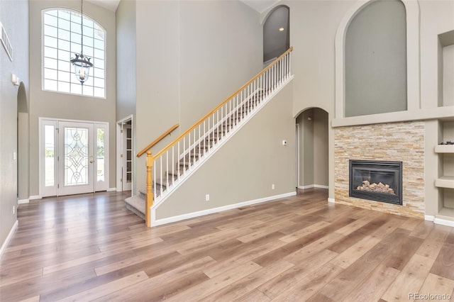 29852 E 163rd Pl, Brighton, CO 80603 - unfurnished living room featuring arched walkways, a high ceiling, wood-type flooring, stairs, and a stone fireplace