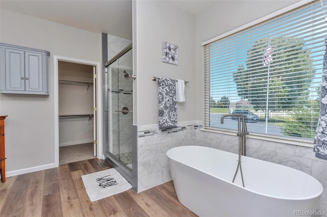 29852 E 163rd Pl, Brighton, CO 80603 - bathroom featuring tile walls, a freestanding tub, plenty of natural light, wood finished floors, and a wainscoted wall