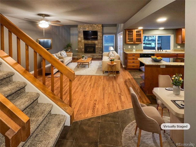 living room featuring sink, dark wood-type flooring, a fireplace, and ceiling fan