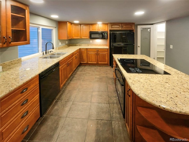 kitchen featuring light stone counters, sink, and black appliances