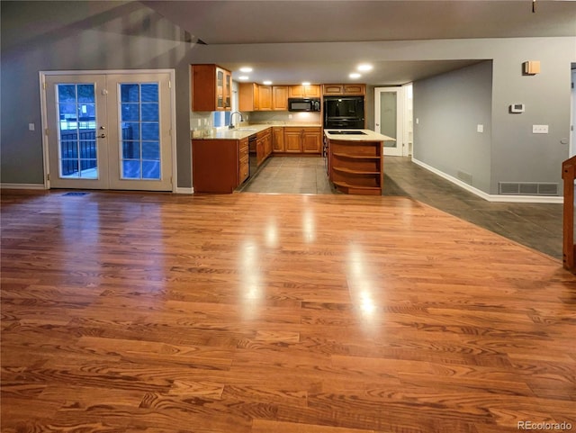 kitchen with sink, a center island, light hardwood / wood-style floors, black appliances, and french doors