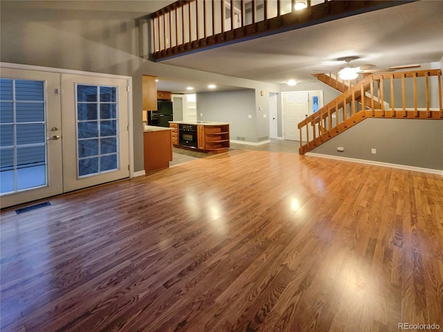 unfurnished living room featuring wood-type flooring, ceiling fan, and french doors