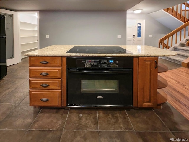 kitchen featuring light stone countertops and black appliances