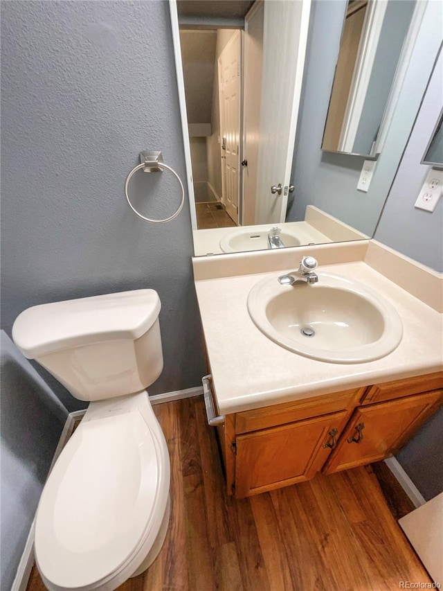 bathroom featuring vanity, wood-type flooring, and toilet