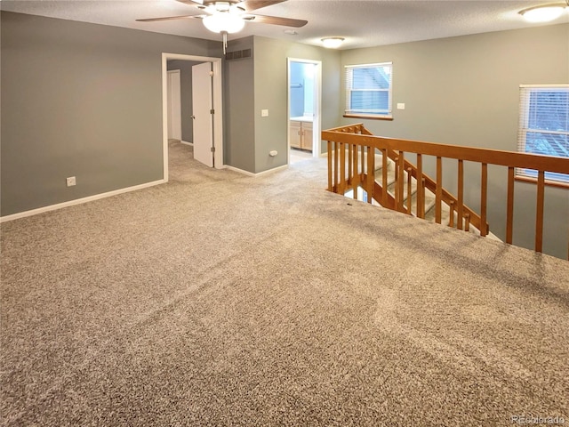 empty room with ceiling fan, carpet, and a textured ceiling