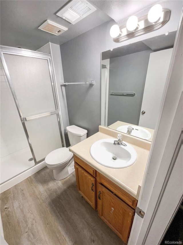 bathroom featuring vanity, toilet, a shower with door, and hardwood / wood-style floors