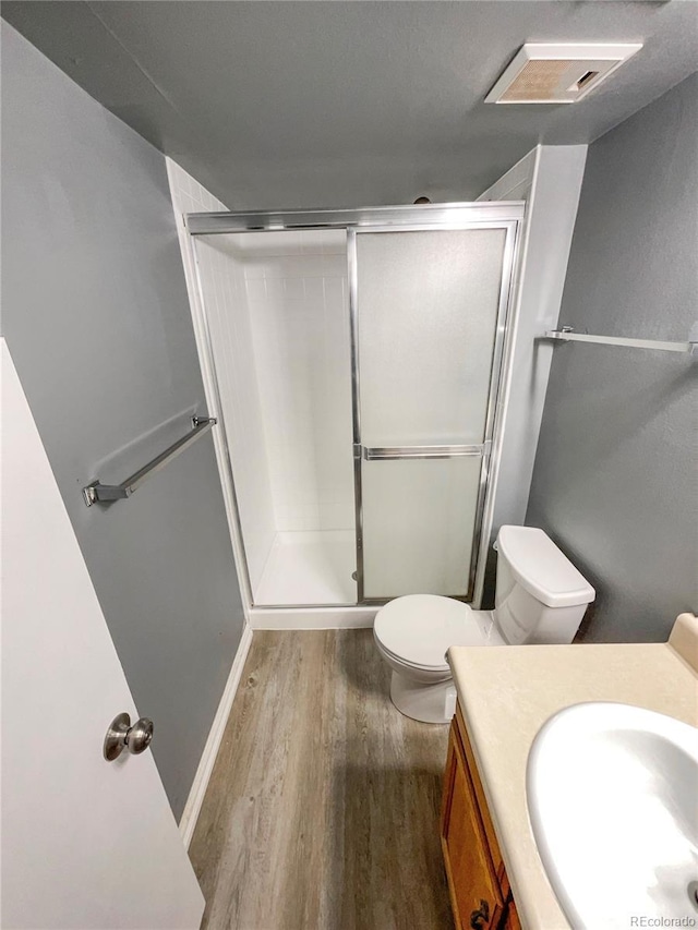 bathroom with vanity, hardwood / wood-style flooring, toilet, and walk in shower