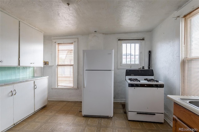 kitchen with a textured ceiling, white appliances, and white cabinetry