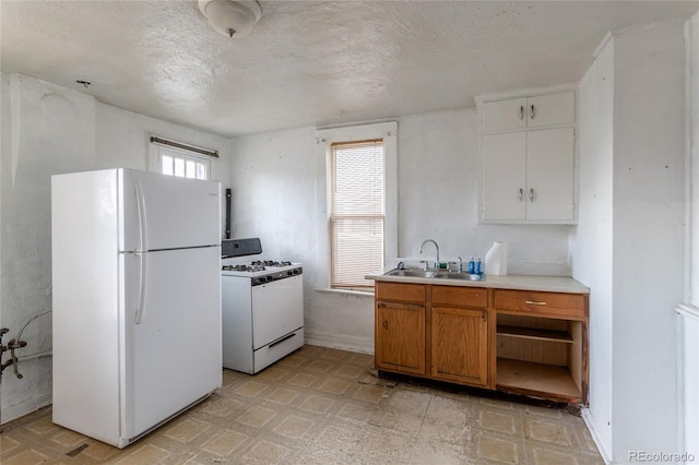 kitchen with sink, white appliances, a textured ceiling, and plenty of natural light