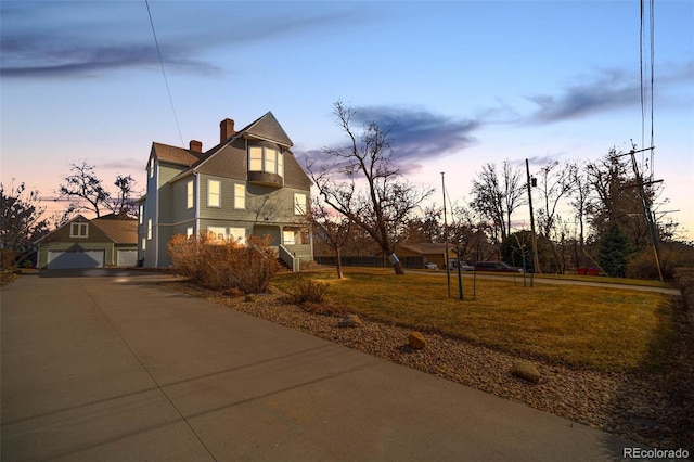 property exterior at dusk featuring an outdoor structure, a lawn, a garage, and a chimney